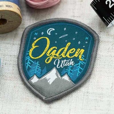 Embroidered shield patch for Ogden, Utah, with mountain skyline, night sky, moon, stars, and pine trees.