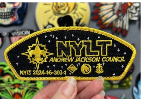 Embroidered black NYLT Andrew Jackson Council scout shoulder patch with fleur-de-lis and star field.
